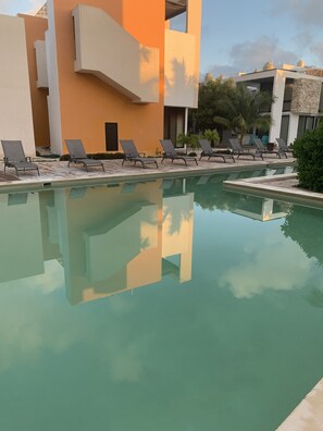 Relax by the serene pool surrounded by modern architecture and calm water.