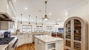 A spacious kitchen with white cabinetry, a large island, and a wooden floor.