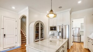 A kitchen with white cabinetry, stainless steel appliances, and a marble countertop.