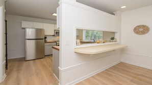 A modern kitchen with white cabinetry, a stainless steel refrigerator, and a wooden countertop.