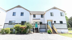 A two-story building with a central entrance, a staircase, and a small porch area.