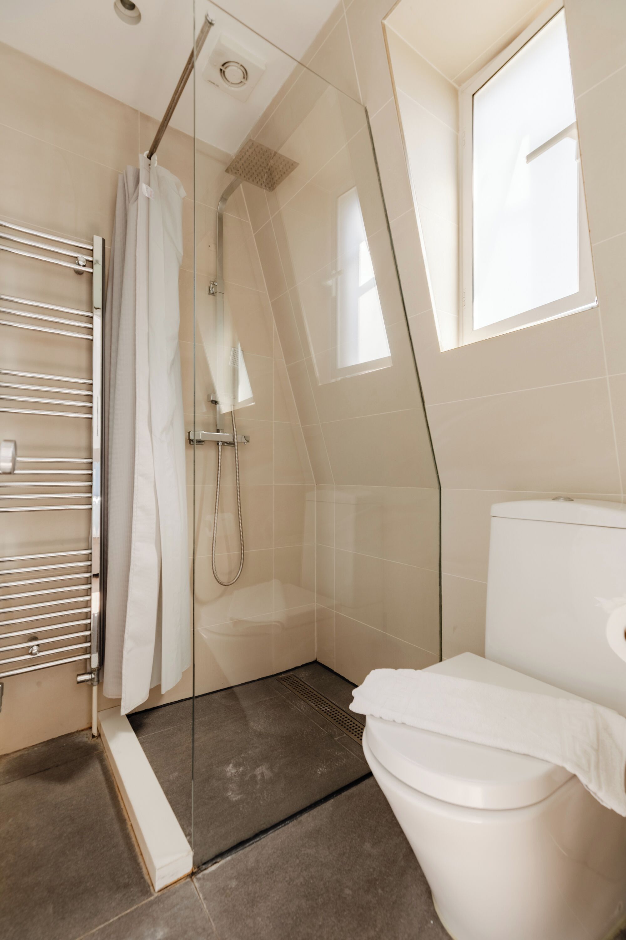 Un baño moderno con cabina de ducha de vidrio, inodoro blanco y barra para toallas.