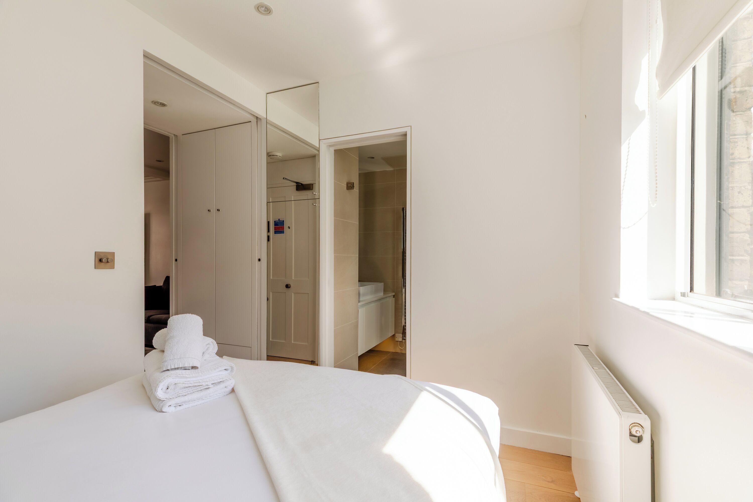 Een slaapkamer met een bed, een radiator en een raam.