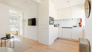 A modern kitchen with white cabinets, a built-in oven, and a coffee machine. - Soho by Excel Apartments (London)