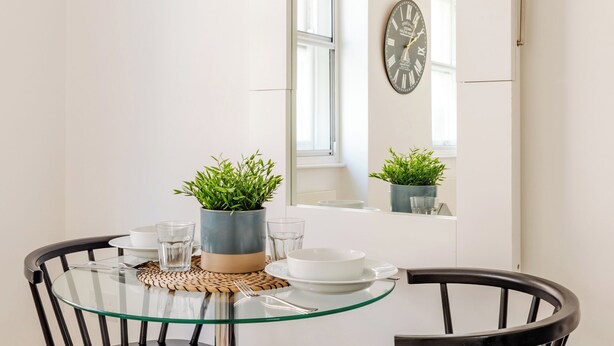 A dining area with a glass table, black chairs, and a potted plant. - Soho by Excel Apartments (London)
