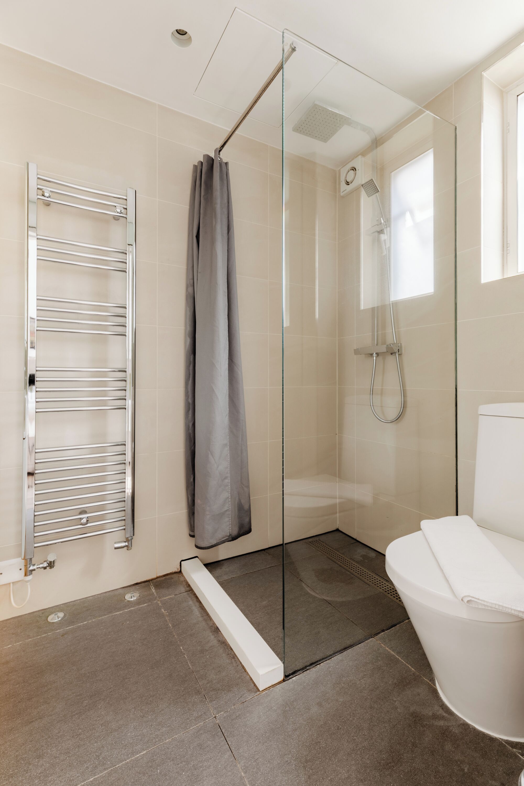 A modern bathroom with a glass-enclosed shower, a white toilet, and a towel rack.
