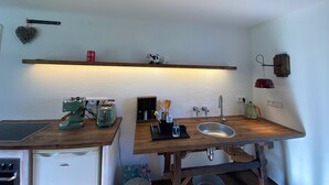 Uma cozinha compacta com bancada de madeira, pia embutida, máquina de café e torradeira.