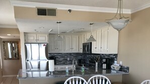 A modern kitchen with white cabinetry, a central island, and a dining area with white chairs.