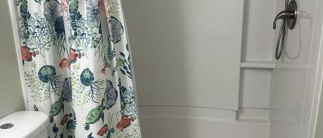 A bathroom with a shower, toilet, and a curtain with a marine theme.