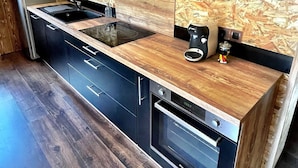 A modern kitchen with wooden cabinetry, a built-in oven, and a coffee maker on the counter.