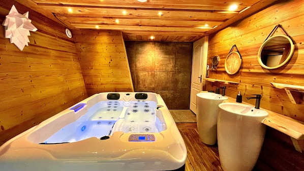 A wooden cabin bathroom with a hot tub, two sinks, and a mirror.