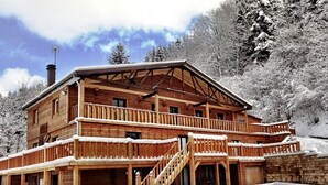 A wooden cabin with a balcony and a staircase leading to the entrance.