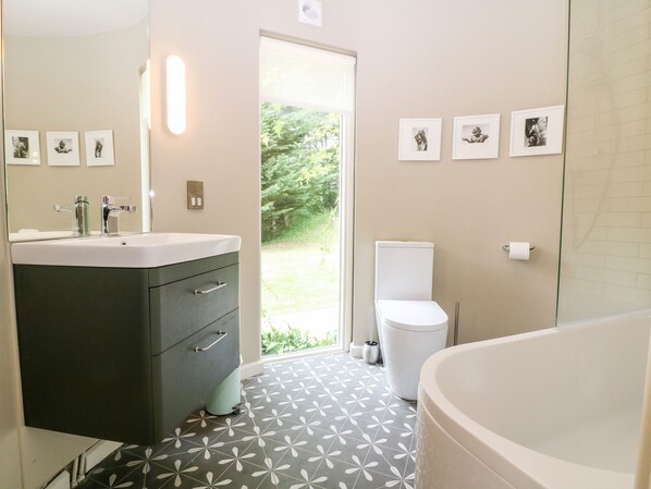 A modern bathroom with a sink, mirror, toilet, and bathtub.