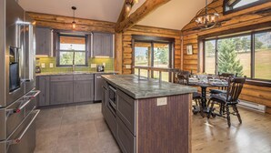 Una cocina moderna con una isla central, vigas de madera y grandes ventanas que ofrecen vistas al exterior.