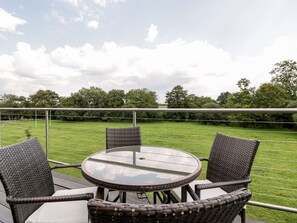 A round glass table with wicker chairs on an outdoor patio.