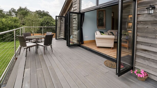 Une terrasse moderne avec une porte vitrée donnant sur un espace de vie comprenant un canapé et une table à manger.