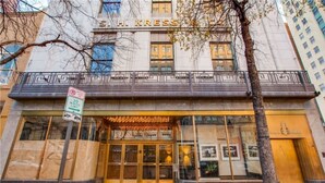 The exterior of the S.H. Kress Building with a 30-minute parking limit sign, large glass entrance, and a tree in the foreground.
