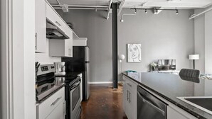 A modern kitchen with stainless steel appliances, a black countertop, and a minimalist design.