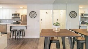 Eine moderne Küche mit weißen Schränken, einem Holztisch und zwei Barhocker.