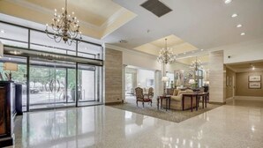 Eine großzügige Lobby mit einem glänzenden Boden, einer imposanten Chandelier und einer Sitzecke mit Tisch und Stühlen.