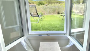 Ein Zimmer mit großem Fenster und Blick auf einen Rasen mit Zaun und einem Stuhl.