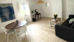 Ein modernes Wohnzimmer mit Essbereich, einer Couch, einem Couchtisch und einer Topfpflanze.