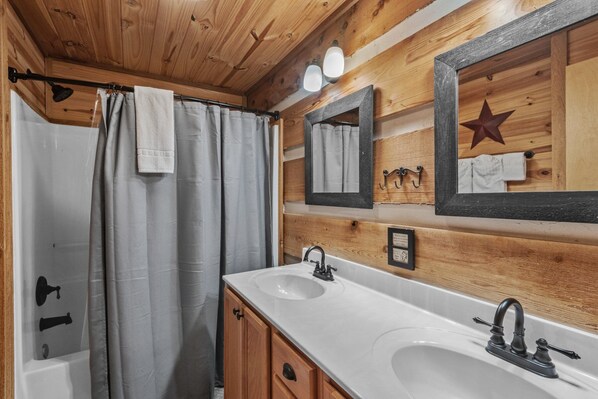 A wooden cabin bathroom with a shower, two sinks, and a mirror with a star decoration. - Farallon- Cozy Cabin with hot tub, fire pit, wood fireplace! (Banner Elk)