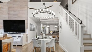 A modern kitchen with a large flat-screen TV, white cabinetry, and a dining area with a white table and chairs. - JUST FINISHED RENOVATIONS 2023!!! A lavishly styled ski-in/out winter escape! (Brian Head)