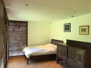 Cozy retreat with a single bed, wooden floor, and framed artwork.