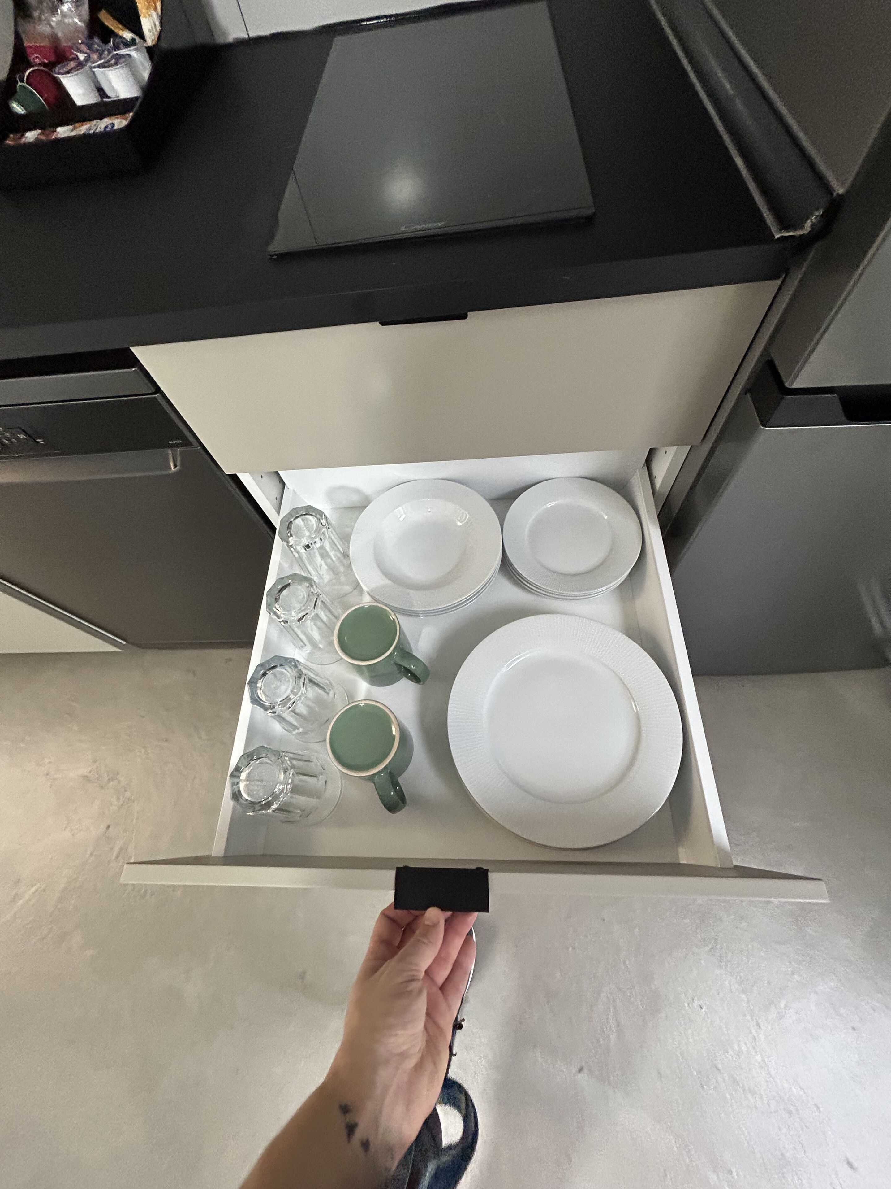 Een keukublade met witte borden, groene mokken en glazen.