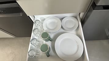 Een keukublade met witte borden, groene mokken en glazen.