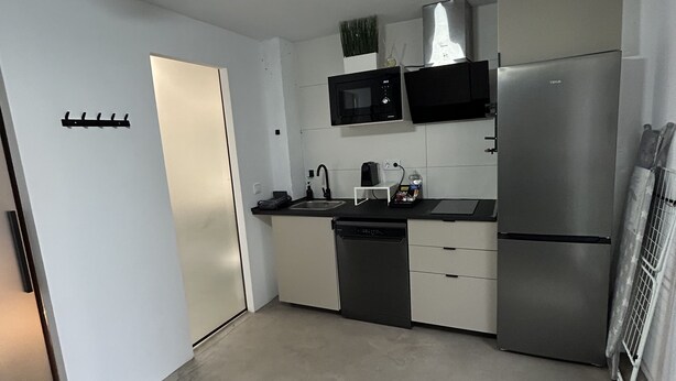 A modern kitchen with white cabinets, a microwave, a dishwasher, and a refrigerator.