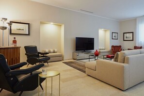 Una sala de estar moderna con un sofá, sillones, un televisor y una mesa de centro.