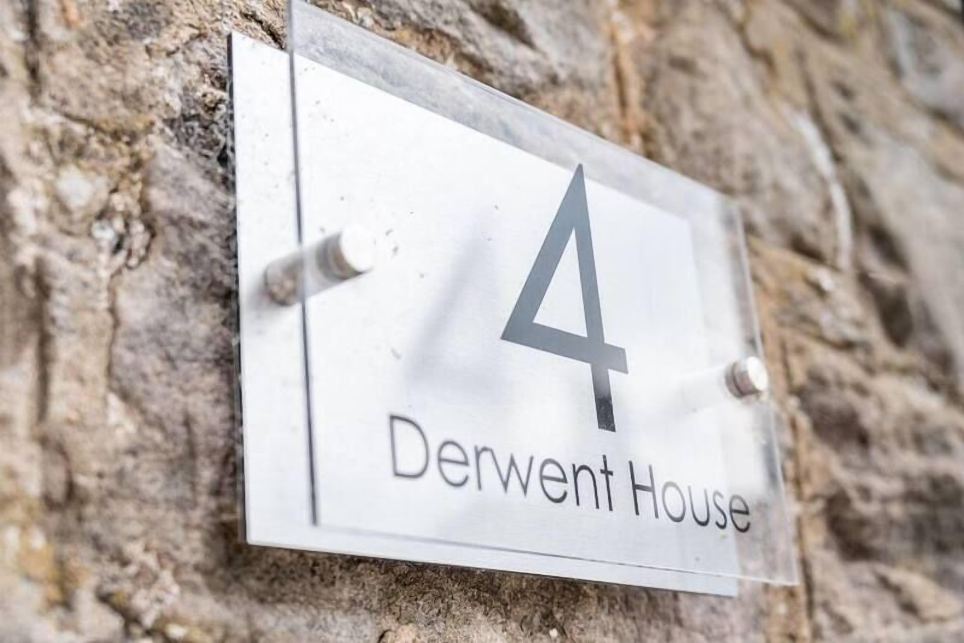 A house number sign for 'Derwent House' mounted on a stone wall.