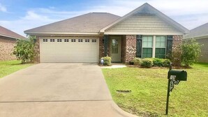 A single-story house with a garage, a front lawn, and a mailbox. - Peaceful 3BR/2BA Hidden Lake Home Near ACOM w/WiFi (Dothan)