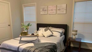 A bedroom with a bed, bedside tables, a nightstand, a lamp, and a window with blinds. - Peaceful 3BR/2BA Hidden Lake Home Near ACOM w/WiFi (Dothan)