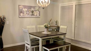 A dining room with a dark wooden table and white chairs, a chandelier, and a painting on the wall. - Peaceful 3BR/2BA Hidden Lake Home Near ACOM w/WiFi (Dothan)