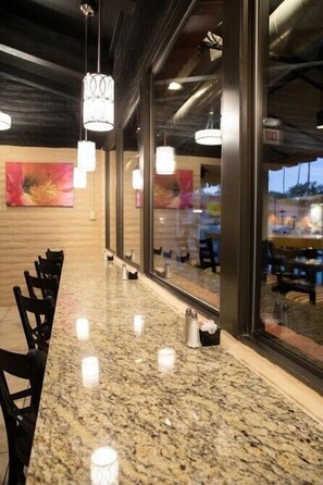 Enjoy meals and meetings in a modern space with large windows offering views of the outside and a stylish pendant light fixture.