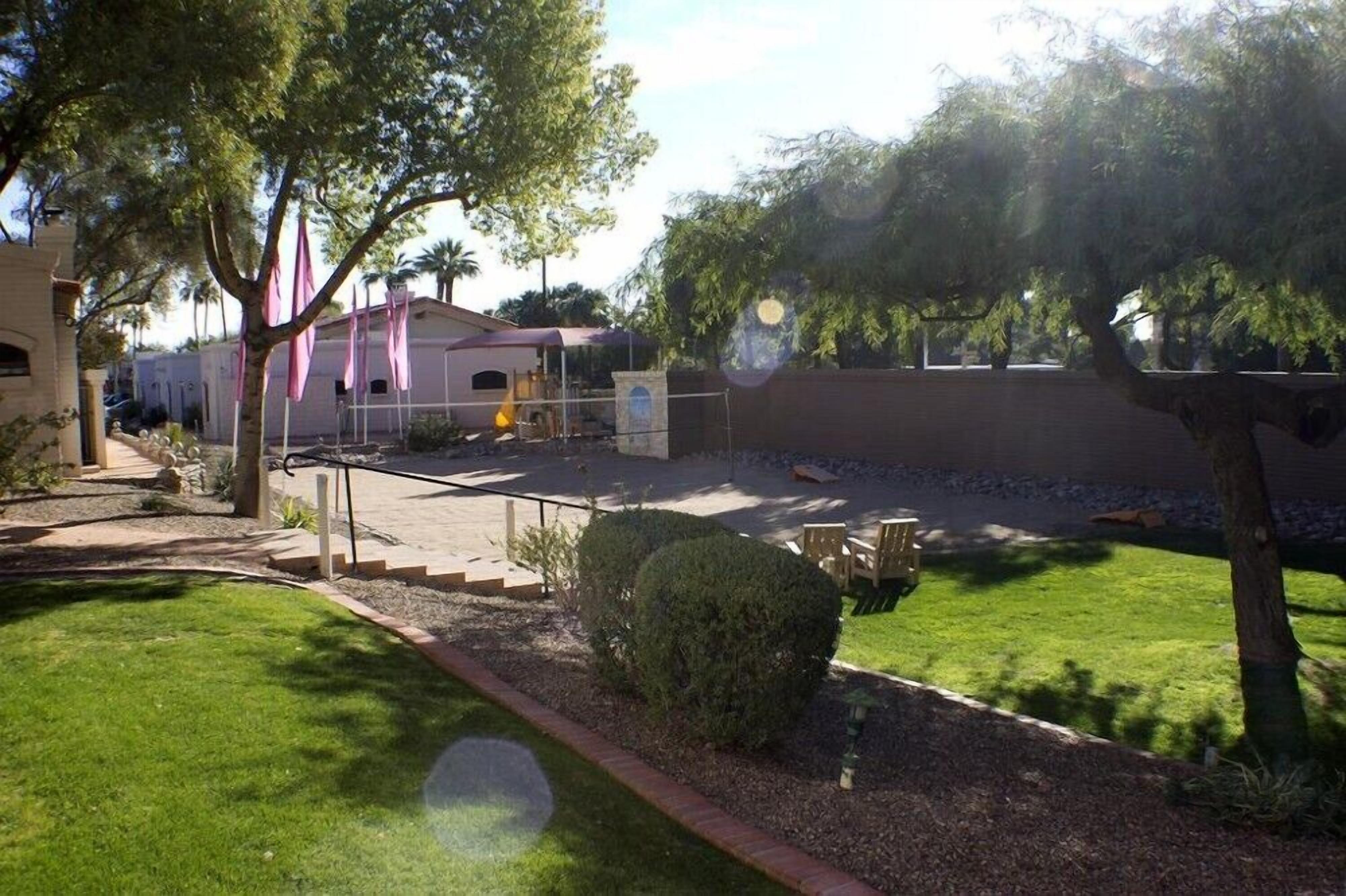 A courtyard with a fenced area, a building with a red roof, and a well-maintained lawn.