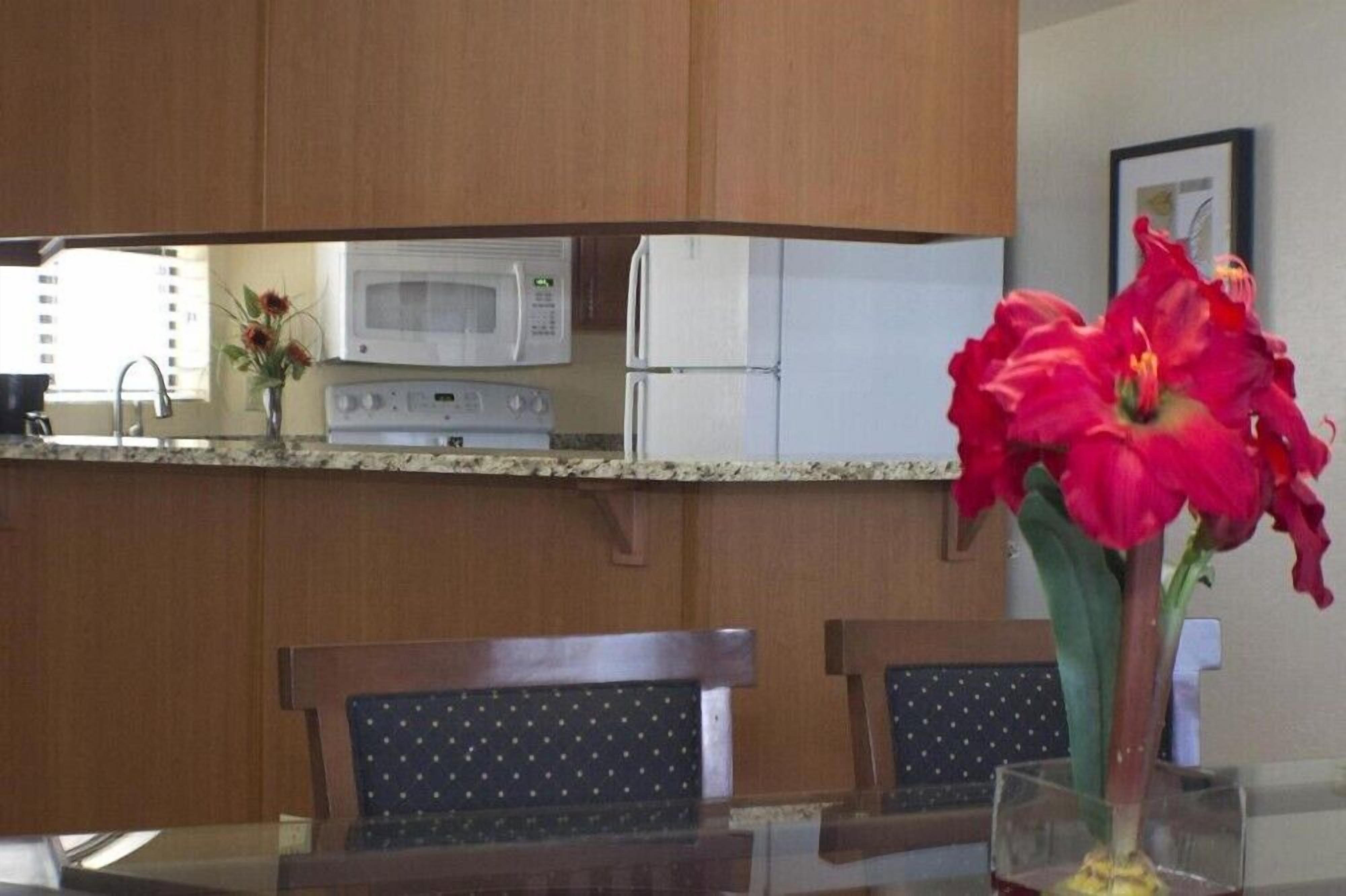 A kitchen with a microwave, refrigerator, and a dining table with chairs.