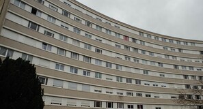 A multi-story building with a curved facade, featuring numerous windows and balconies. - Spacious, modern T3, near metro and RER station (Créteil)