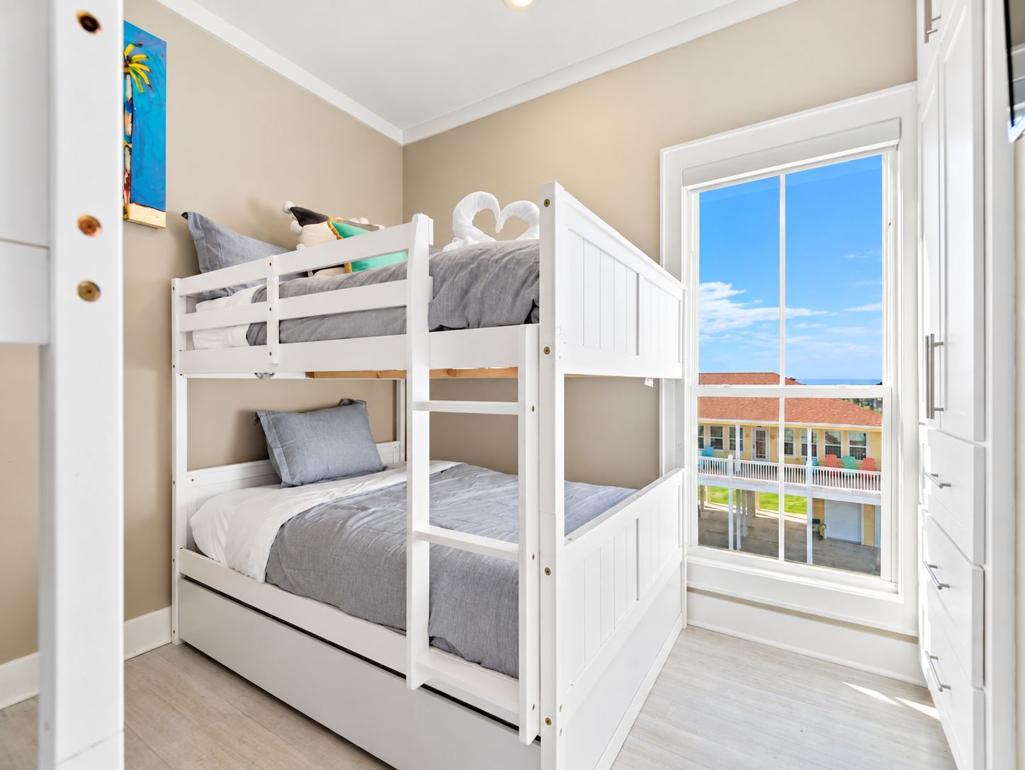 Family-friendly bunk room with built-in white bunk beds and a nearby window bringing in natural light.
