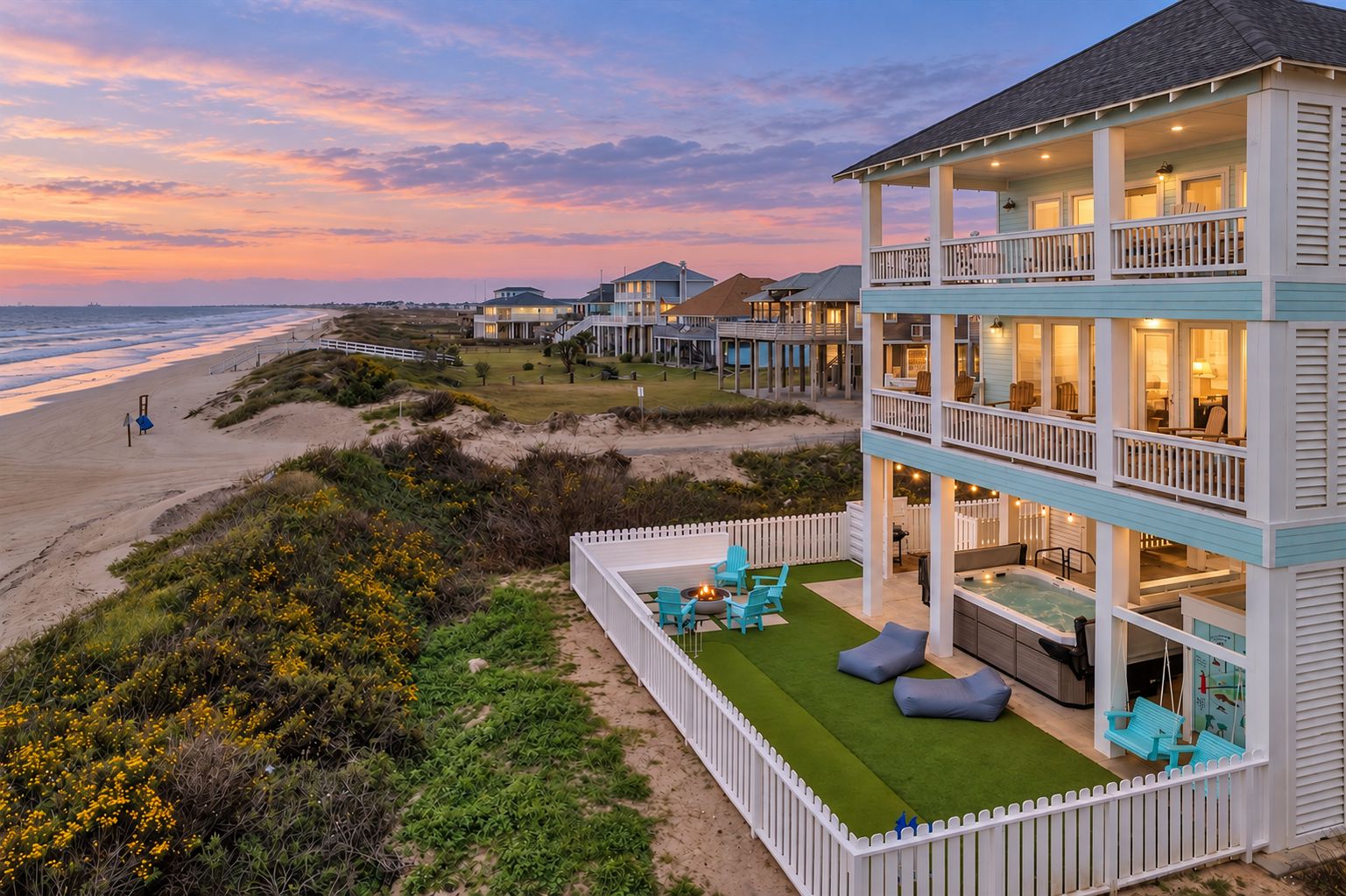 Twilight aerial view of this beachfront Crystal Beach home, highlighting its fenced outdoor lounge area, multi-level decks, and direct proximity to the Gulf shoreline.