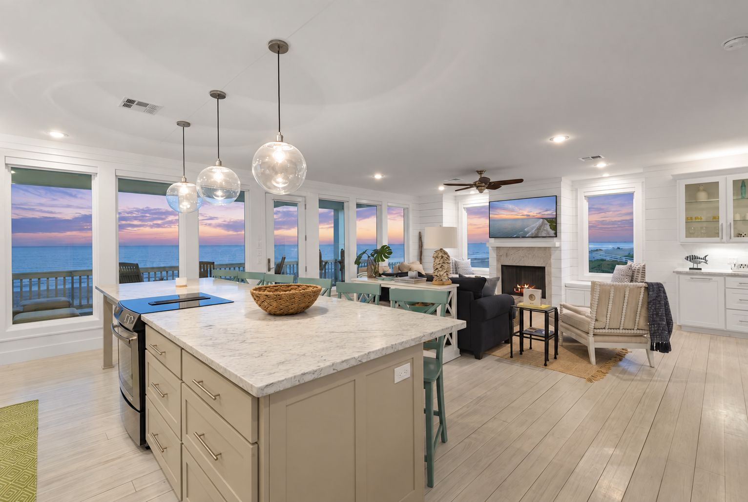 A spacious kitchen with a large island, pendant lights, and a view of the ocean.