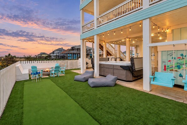 A two-story building with a covered outdoor patio, a fire pit, and outdoor seating. - Beachfront Retreat with SwimSpa | Putt-Putt | Fire Pit | Sleeps 16 (Bolivar Peninsula)