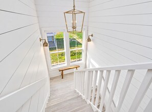 A staircase with white railings leading to a window overlooking a garden. - Beachfront Retreat with SwimSpa | Putt-Putt | Fire Pit | Sleeps 16 (Bolivar Peninsula)