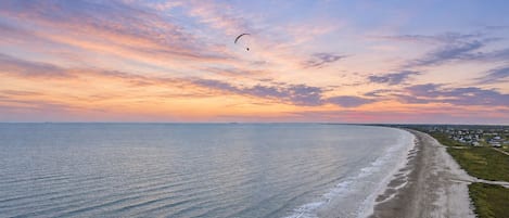 A coastal landscape with a beach, ocean, and a distant shoreline with buildings.