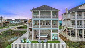 Une maison à plusieurs étages située en bord de mer, dotée d’un balcon, d’un espace salon extérieur et d’un jacuzzi.