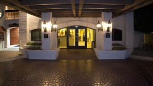 A hotel entrance with a brick facade, a covered walkway, and two illuminated signs. - Scottsdale Camelback Resort Peaceful Studio with Outdoor Pool (Scottsdale)