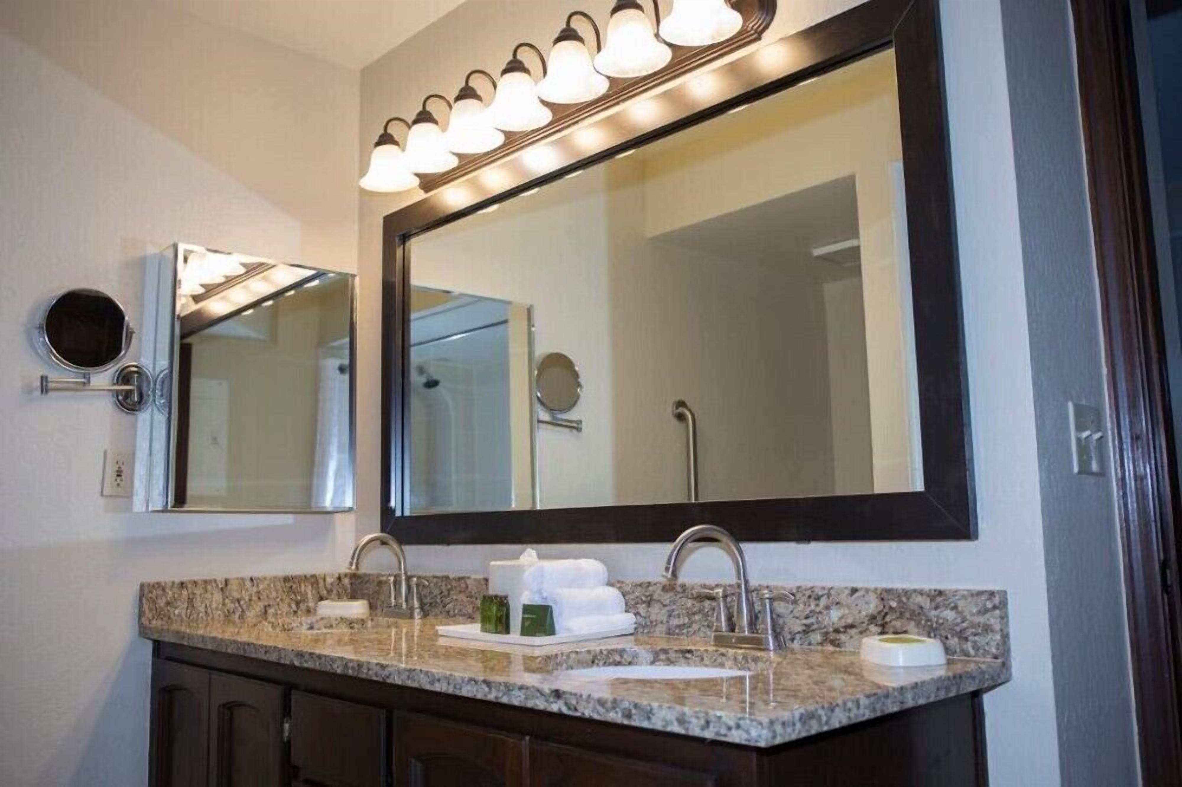 Une salle de bain avec un grand miroir, deux lavabos et un meuble-lavabo.